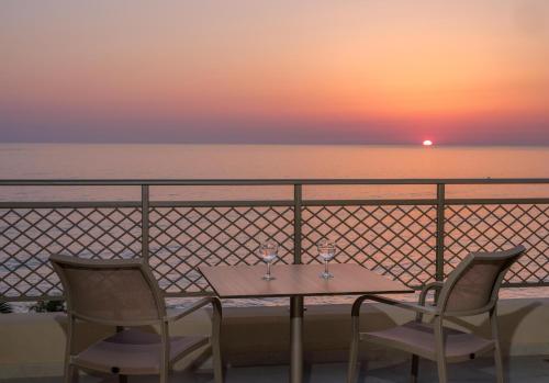 a table and two chairs with a sunset in the background at Nana Golden Beach All Inclusive Resort & Spa in Hersonissos