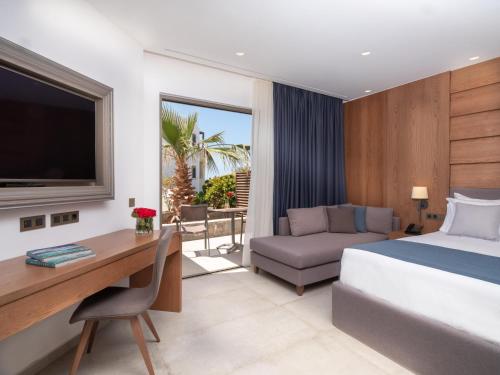 a bedroom with a bed and a desk and a tv at Nana Golden Beach All Inclusive Resort & Spa in Hersonissos