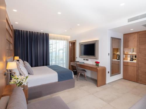 a hotel room with a bed and a desk and a television at Nana Golden Beach All Inclusive Resort & Spa in Hersonissos