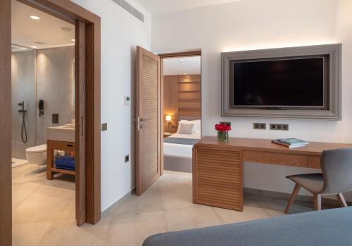 a hotel room with a desk and a television at Nana Golden Beach All Inclusive Resort & Spa in Hersonissos