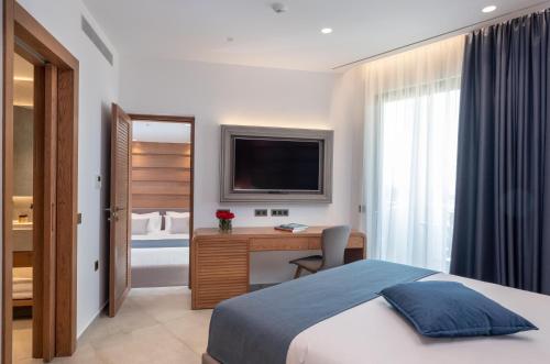 a bedroom with a bed and a desk with a television at Nana Golden Beach All Inclusive Resort & Spa in Hersonissos