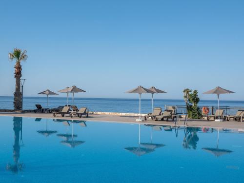 a pool with chairs and umbrellas next to the ocean at Nana Golden Beach All Inclusive Resort & Spa in Hersonissos