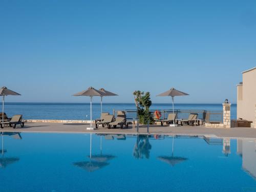 a swimming pool with chairs and umbrellas next to the ocean at Nana Golden Beach All Inclusive Resort & Spa in Hersonissos