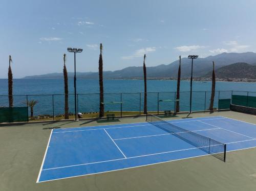 a tennis court with the ocean in the background at Nana Golden Beach All Inclusive Resort & Spa in Hersonissos