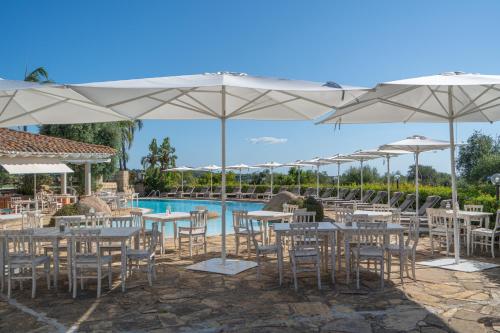 a restaurant with tables and umbrellas next to a pool at Felix Hotels - Galanias Hotel & Retreat in Bari Sardo