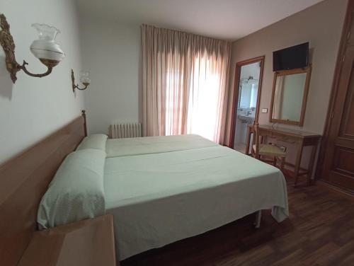a bedroom with a bed and a desk and a mirror at Hotel Galaico in Sanxenxo