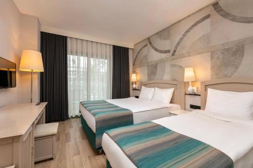a hotel room with two beds and a desk at Greenwood Kemer Resort in Kemer