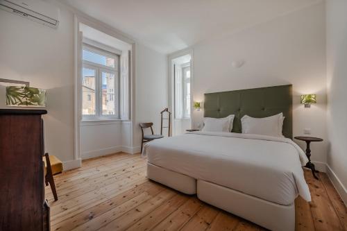 a bedroom with a large white bed and two windows at Casas de São Bento in Lisbon