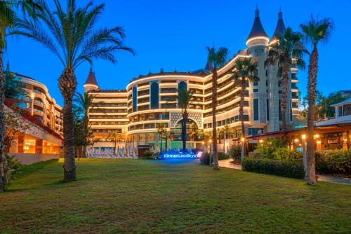 a large building with palm trees in front of it at Leodikya Kirman Premium - Ultra All Inclusive in Okurcalar