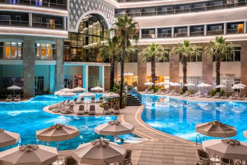 an indoor pool with tables and umbrellas in a building at Leodikya Kirman Premium - Ultra All Inclusive in Okurcalar