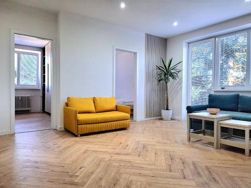 a living room with a yellow couch and blue chairs at Apartmán s pekným výhľadom in Rimavská Sobota