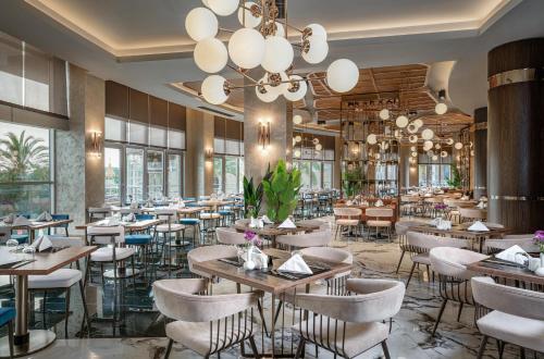 a restaurant with tables and chairs and a chandelier at Leodikya Kirman Premium - Ultra All Inclusive in Okurcalar