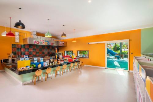 a restaurant with orange walls and a counter with chairs at Leodikya Kirman Premium - Ultra All Inclusive in Okurcalar