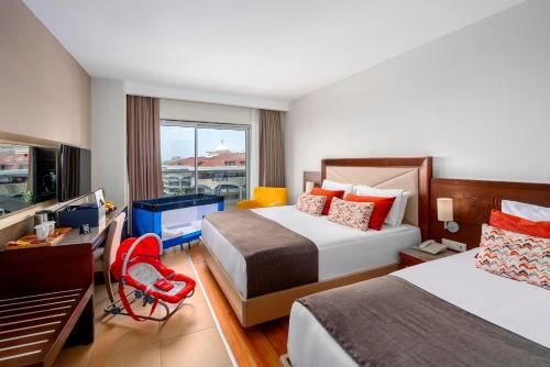 a hotel room with two beds and a desk and a television at Leodikya Kirman Premium - Ultra All Inclusive in Okurcalar