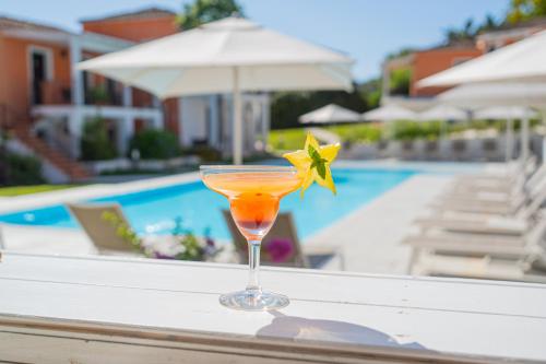 a drink sitting on a table next to a pool at Felix Hotels - Galanias Hotel & Retreat in Bari Sardo