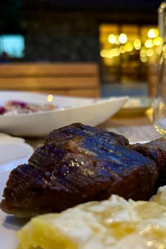 a plate of food with meat and potatoes on a table at NeoKulla Hotel - Hikers Hive in Valbonë