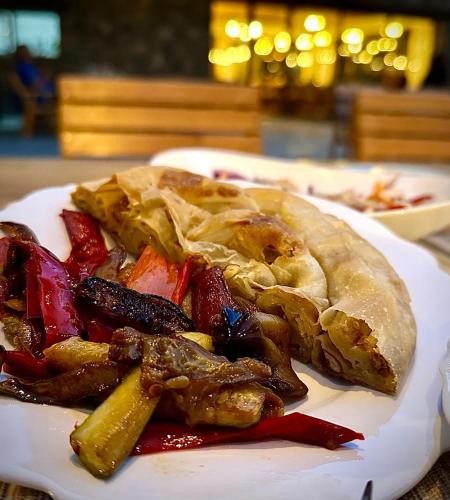 a plate of food with meat and vegetables on a table at NeoKulla Hotel - Hikers Hive in Valbonë