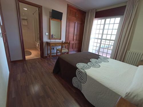 a bedroom with a bed and a desk and a mirror at Hotel Galaico in Sanxenxo