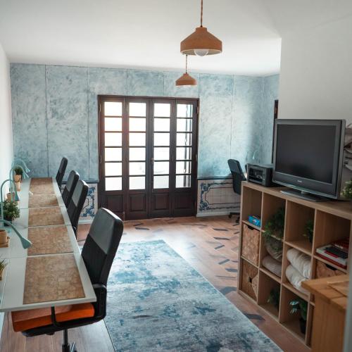 a room with a table and chairs and a television at Behappy Lodge & Brunch in Esmoriz