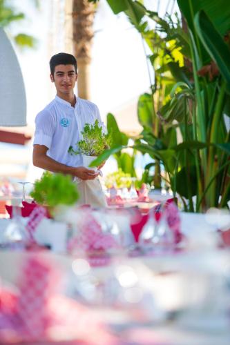 a man holding a bunch of vegetables in front of a table at Miramare Beach Hotel - Ultra All Inclusive in Side