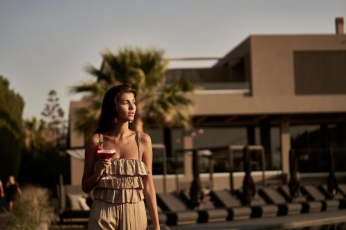 a woman in a dress is holding a drink at NEMA Design Hotel & Spa - Adults Only in Hersonissos