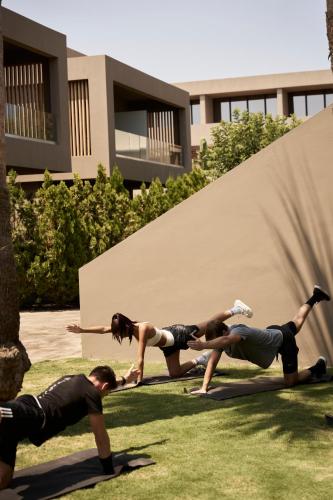 a group of people doing push ups on the grass at NEMA Design Hotel & Spa - Adults Only in Hersonissos