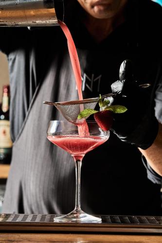 a bartender preparing a strawberry cocktail in a martini glass at NEMA Design Hotel & Spa - Adults Only in Hersonissos