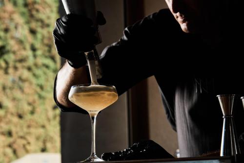 a person pouring a glass of white wine at NEMA Design Hotel & Spa - Adults Only in Hersonissos