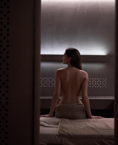 a woman sitting on a bed looking out a window at NEMA Design Hotel & Spa - Adults Only in Hersonissos