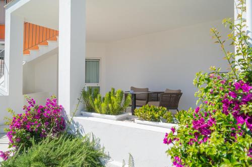 a white house with purple flowers on a balcony at Felix Hotels - Galanias Hotel & Retreat in Bari Sardo