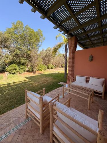 a patio with two benches under a pergola at Appartement standing piscine la palmeraie in Marrakech