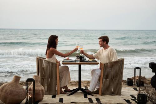 a man and woman sitting at a table on the beach at NEMA Design Hotel & Spa - Adults Only in Hersonissos