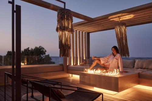 a woman sitting on a couch next to a fire pit at NEMA Design Hotel & Spa - Adults Only in Hersonissos