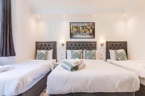 three beds in a room with white walls at The Chapter Hotels - Leisure Inn in London