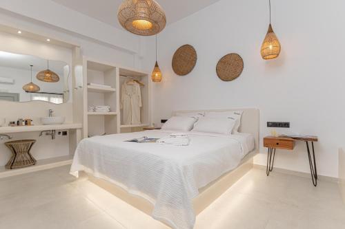 a white bedroom with a white bed and pendant lights at Adama's Suites in Naxos Chora