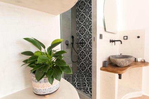 a bathroom with a sink and a potted plant at Adama's Suites in Naxos Chora