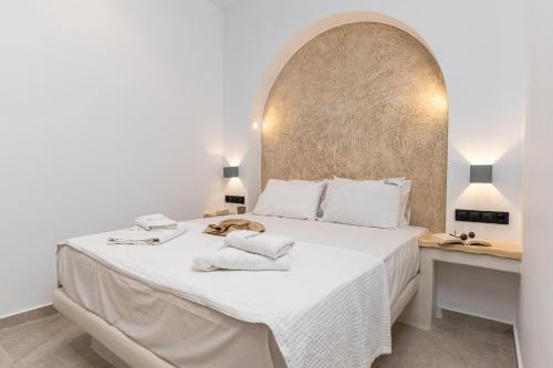 a white bedroom with a large bed with towels on it at Adama's Suites in Naxos Chora
