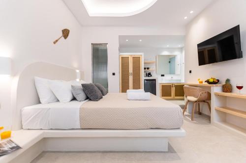 a white bedroom with a bed and a kitchen at Adama's Suites in Naxos Chora