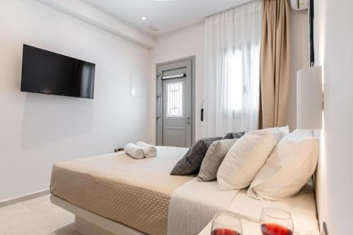 a white bedroom with a bed with two glasses of wine at Adama's Suites in Naxos Chora