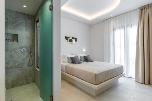 a bedroom with a bed and a walk in shower at Adama's Suites in Naxos Chora