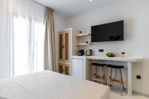 a white bedroom with a bed and two bar stools at Adama's Suites in Naxos Chora