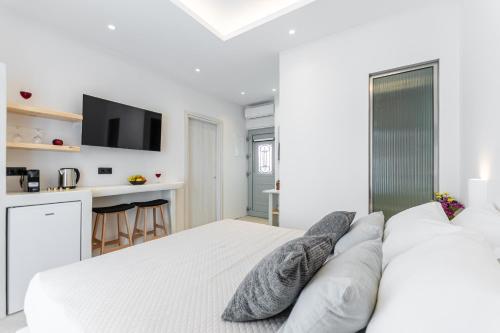 a white bedroom with a large bed with pillows at Adama's Suites in Naxos Chora