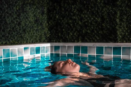 a woman swimming in a swimming pool at night at Side Zeugma Hotel - Adult Only 16 Plus in Side