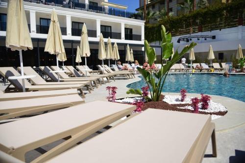 a row of lounge chairs with umbrellas and a pool at Side Zeugma Hotel - Adult Only 16 Plus in Side