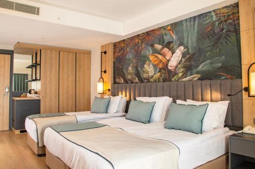 two beds in a hotel room with a painting on the wall at Side Zeugma Hotel - Adult Only 16 Plus in Side