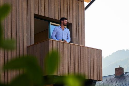 a man standing on a balcony of a building at Hotel UND - smart alpine stay in Schladming