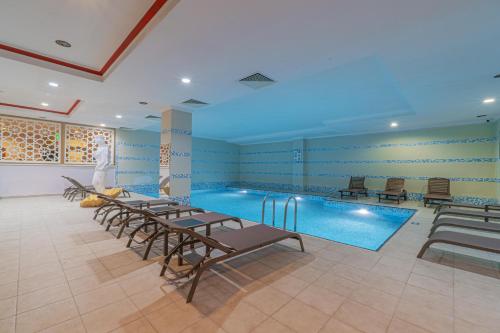 a swimming pool with tables and chairs in a room at Q Ella Beach Hotel in Side