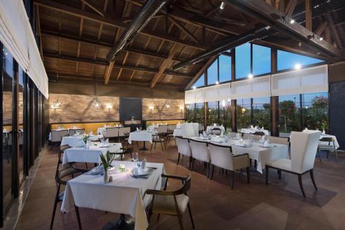 a restaurant with white tables and chairs and windows at Trendy Lara in Lara