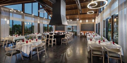 a restaurant with white tables and chairs and windows at Trendy Lara in Lara