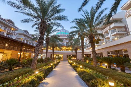 a walkway in front of a building with palm trees at Kirman Belazur Resort & Spa in Belek